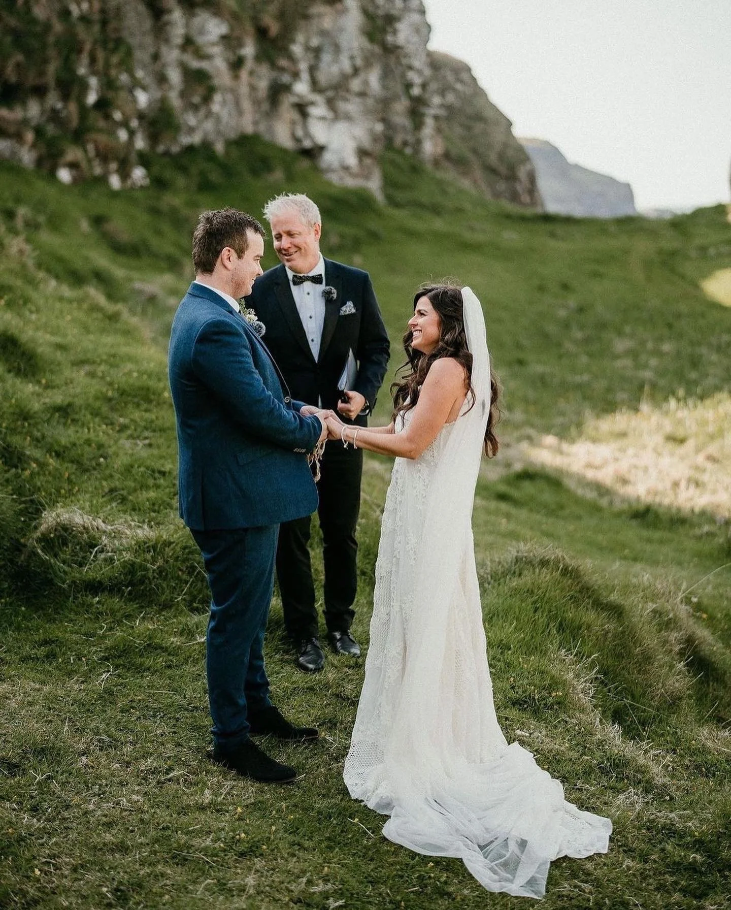 A couple getting married in Ireland, cliffs in the background. Smiling minister.